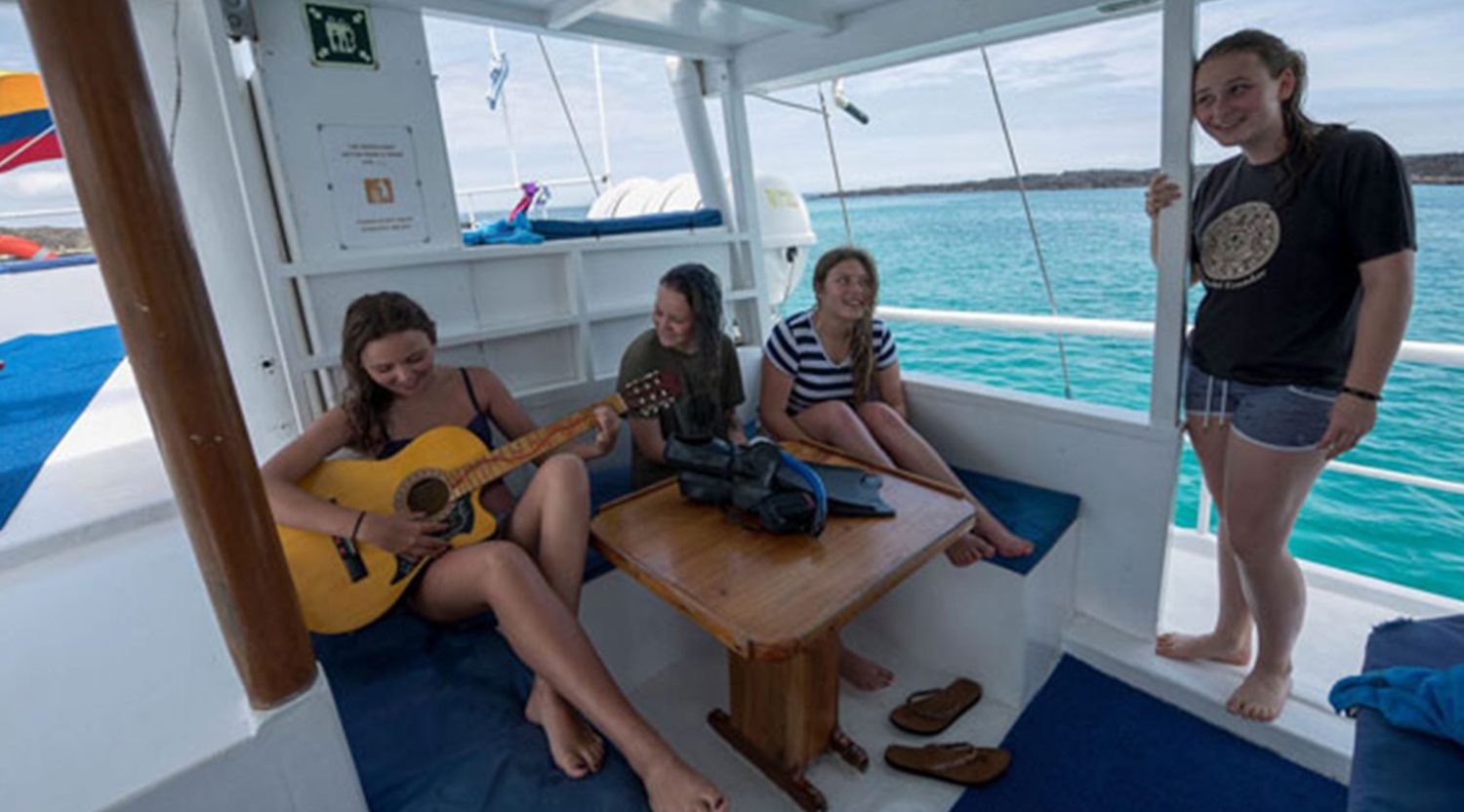 tourist playing guitar in the deck of golondrina yacht of galapagos islands