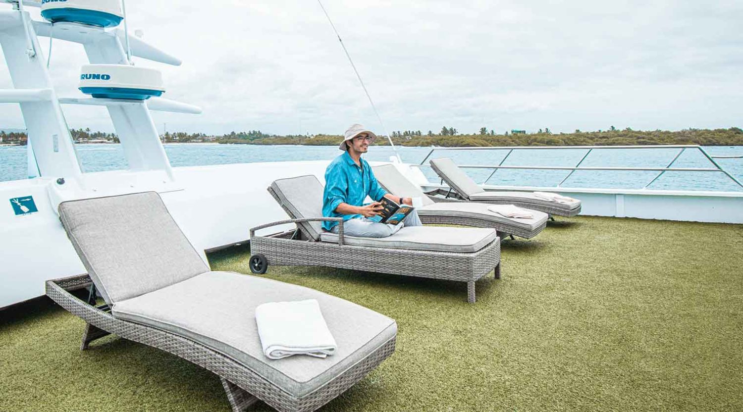 tourist reading in anahi catamaran yacht deck of galapagos islands tours