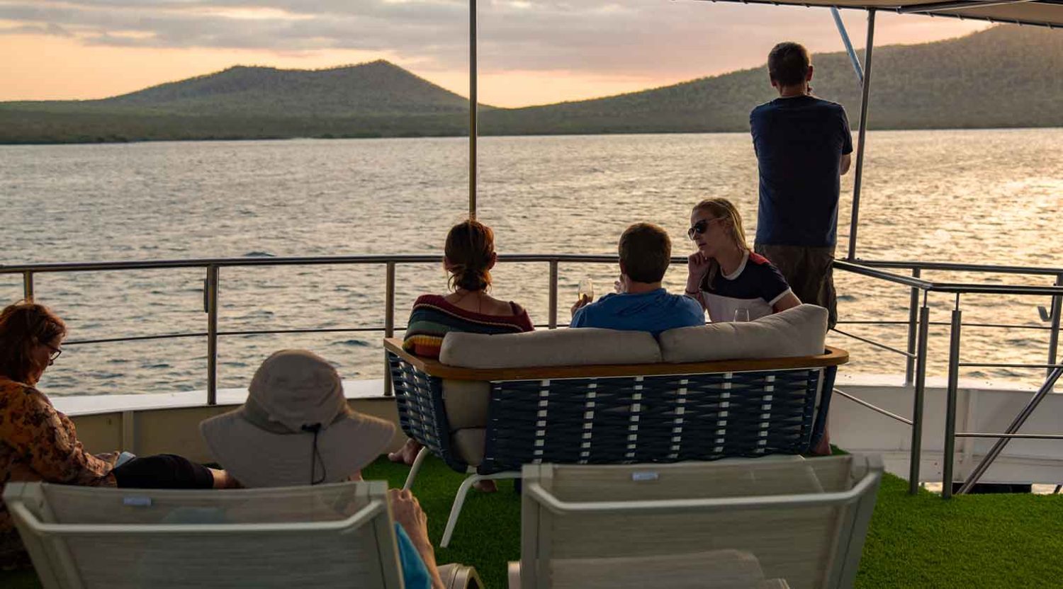 tourists talking on the deck during the sunset in bonita yacht of galapagos islands tours