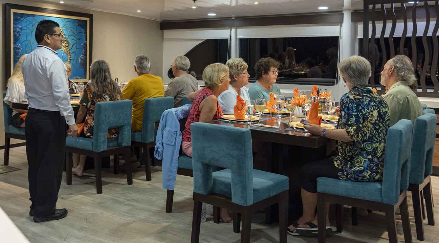tourists having dinner in the dining room of Eco Galaxy Yacht of galapagos islands tours