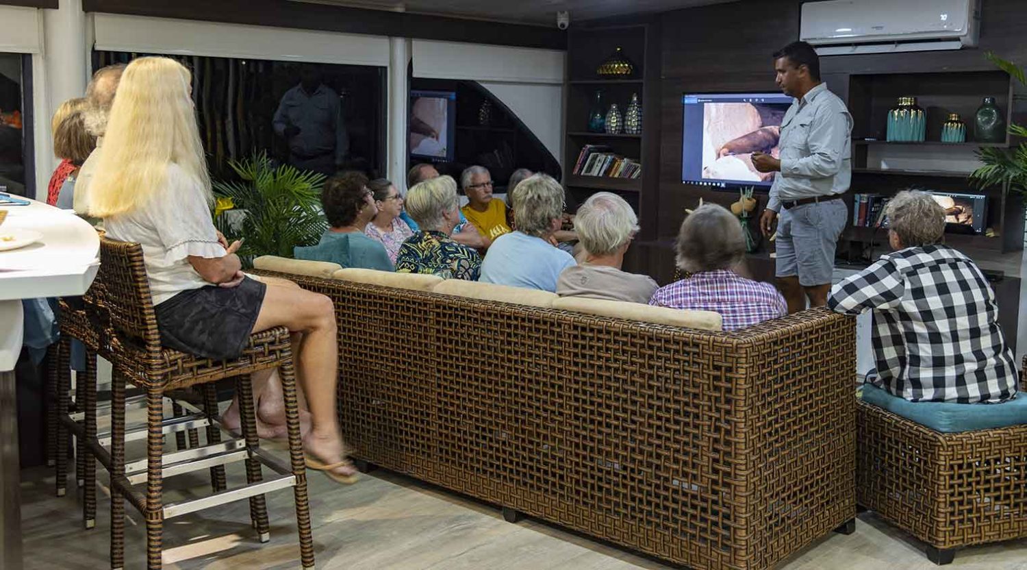 tourists getting instructions of the living room of eco galaxy yacht of galapagos islands tours