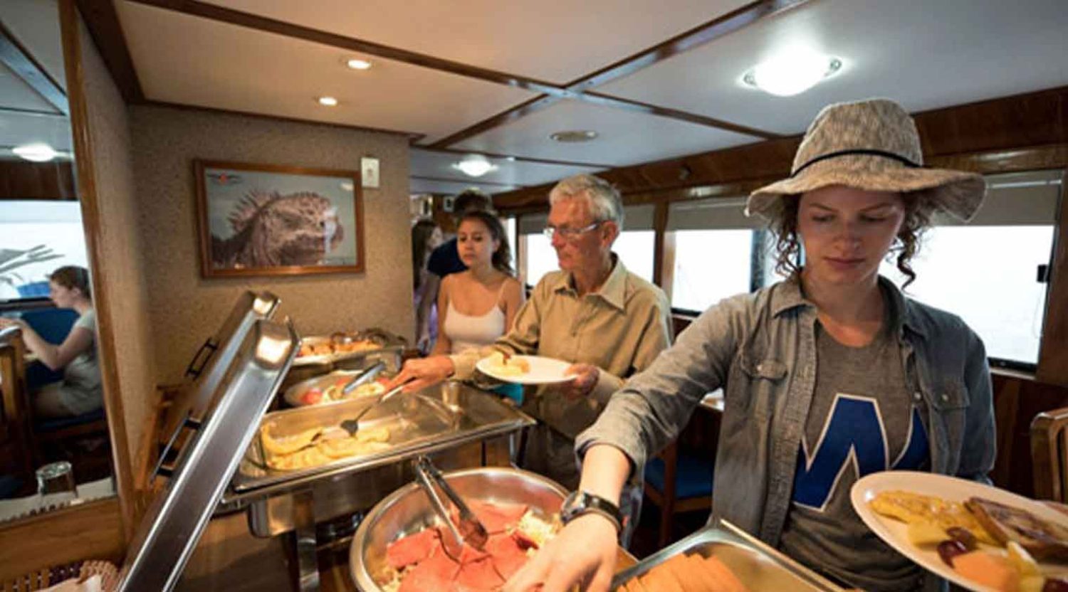 tourists getting lunch in the fragta yacht of galapagos islands tours