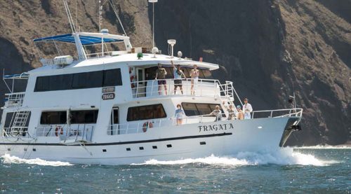 tourist taking a photo on the front deck of fragata yacht of galapagos islands tours