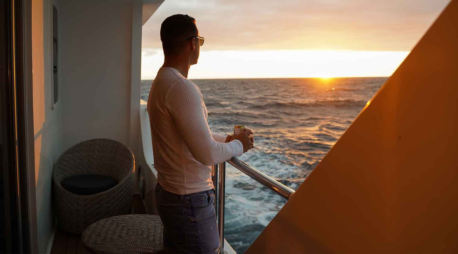 man look at the sunset in infinity yacht balcony of galapagos islands tours